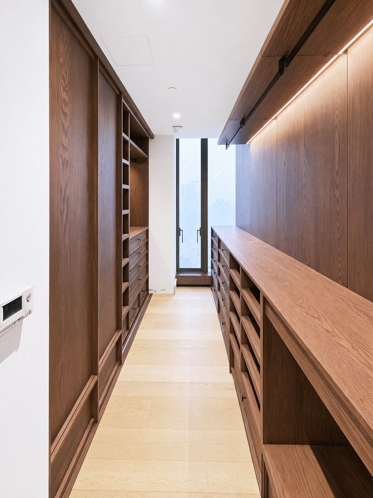 long oak counter over drawer banks facing a corridor of wardrobes, window at the end