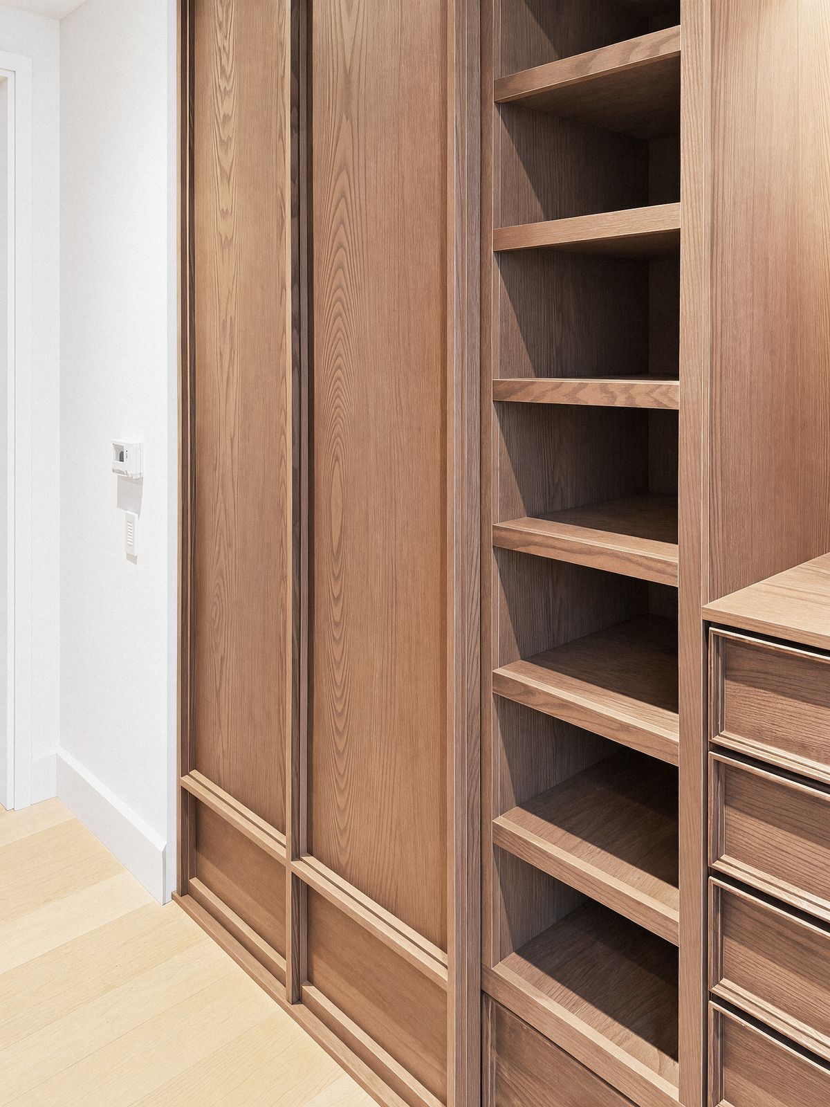 panelled oak wardrobe doors with applied moulding beside open shelving
