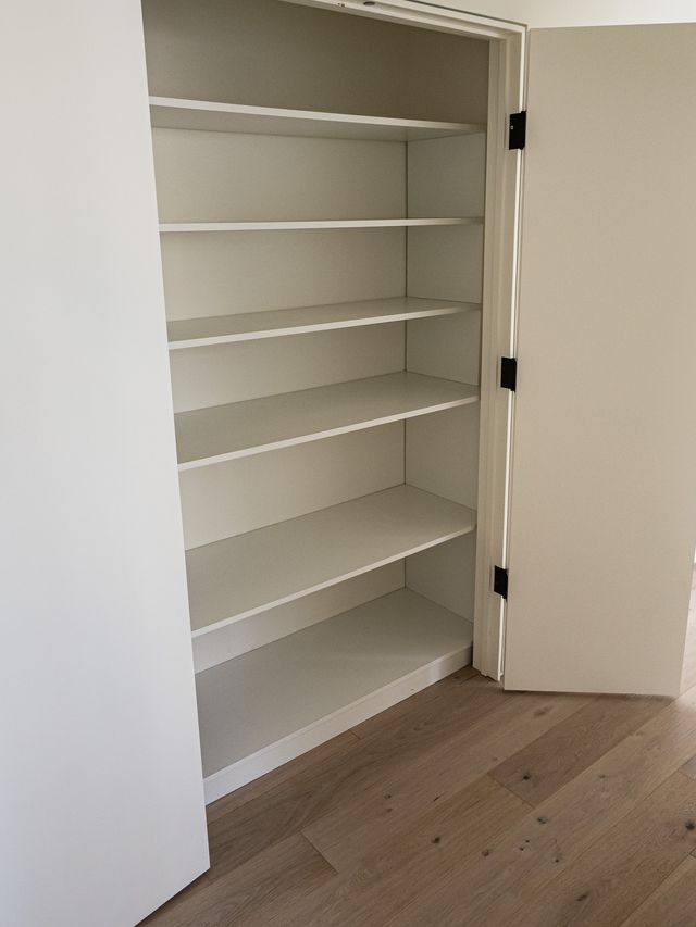 open white pantry closet with black hinge door