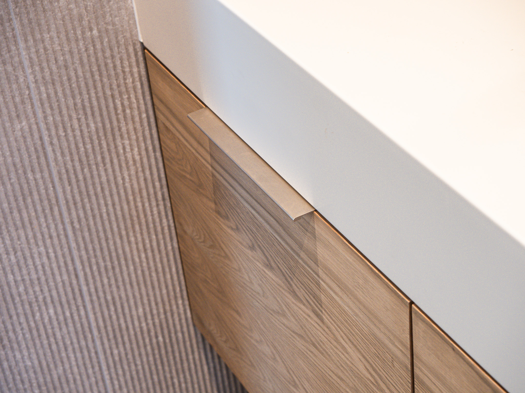 wood vanity corner with white countertop and pull