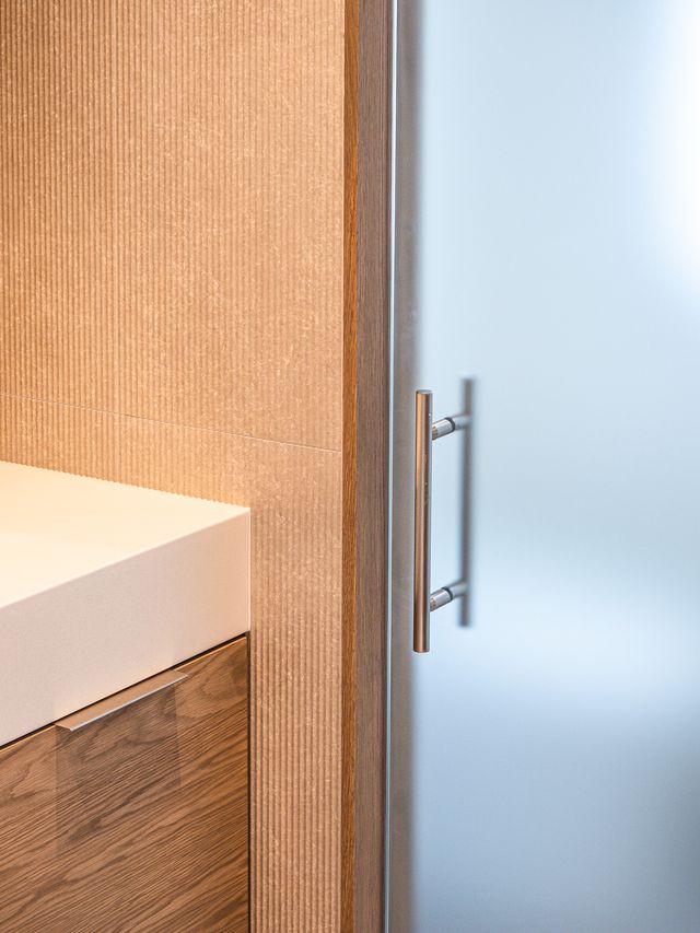 fluted tile wall with wood vanity and glass door