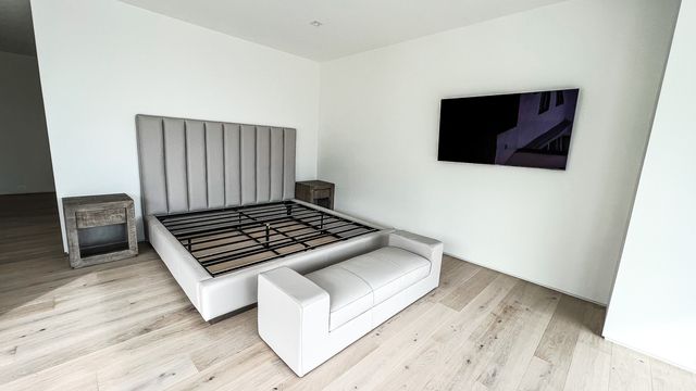 upholstered bed with bench and wall-mounted television