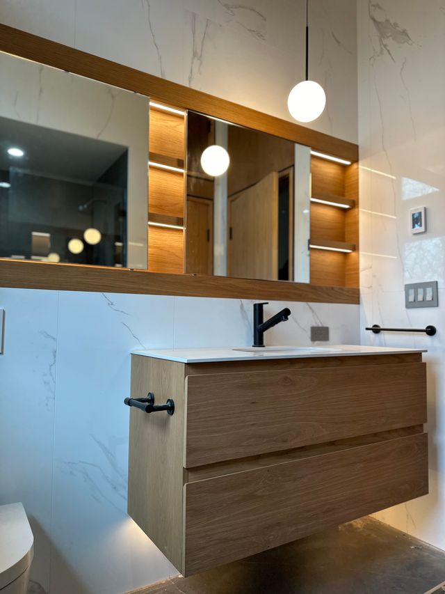 floating wood vanity with marble tile and led mirror