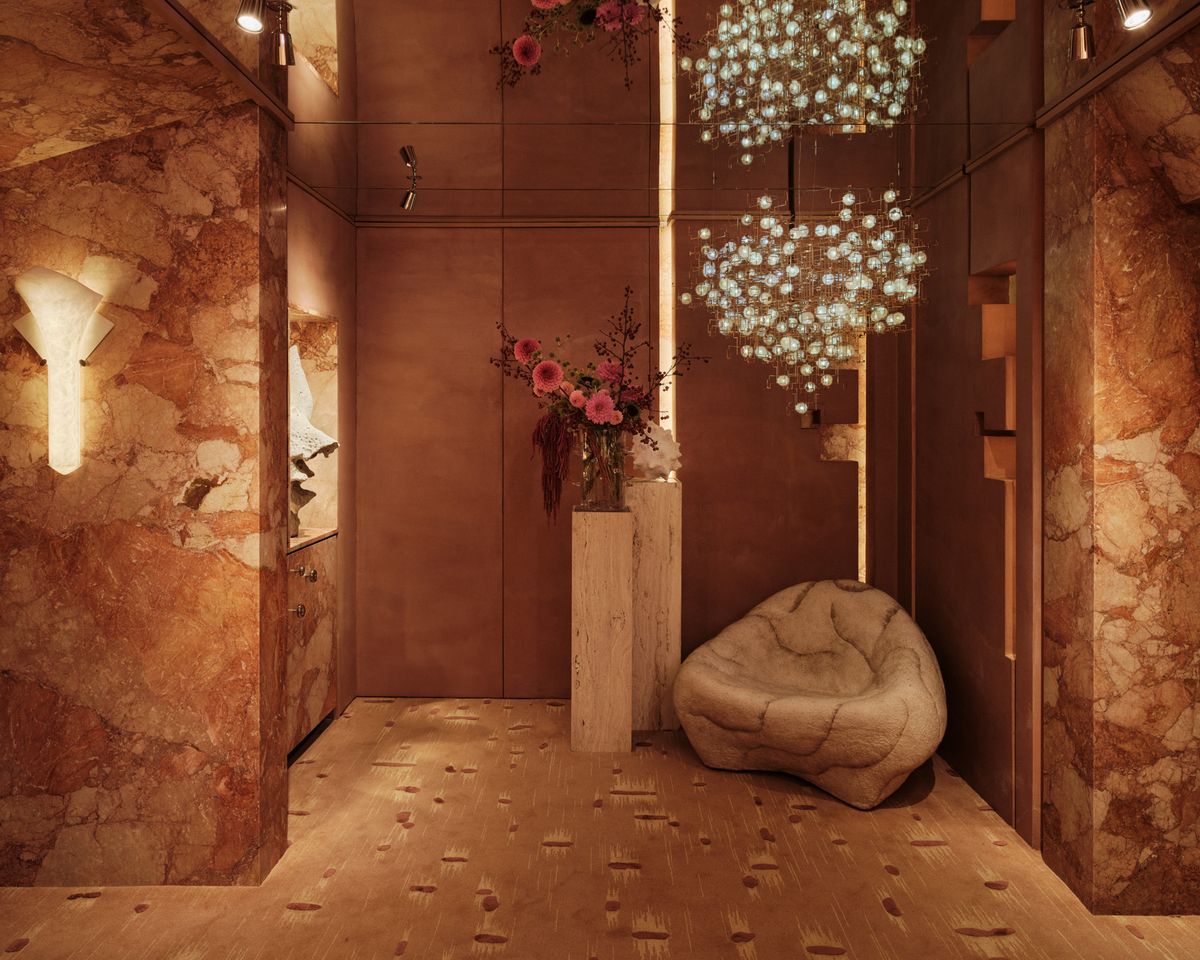 annex with a hanging light above a sculpted lounge chair and a plinth of flowers