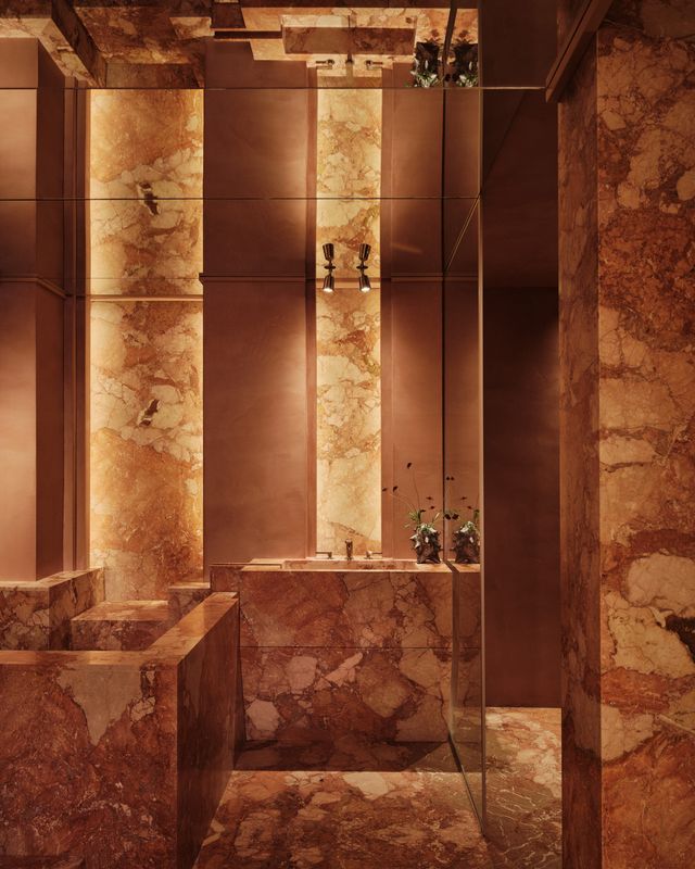 bath with stone columns, flowers on a plinth and a glass screen