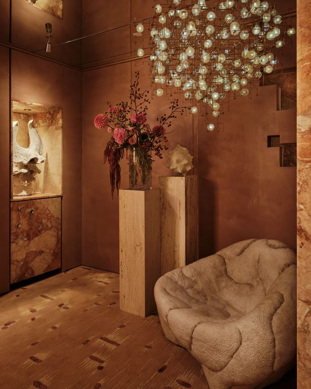 annex corridor with a stone-clad cabinet, a pedestal and a sculpted lounge chair