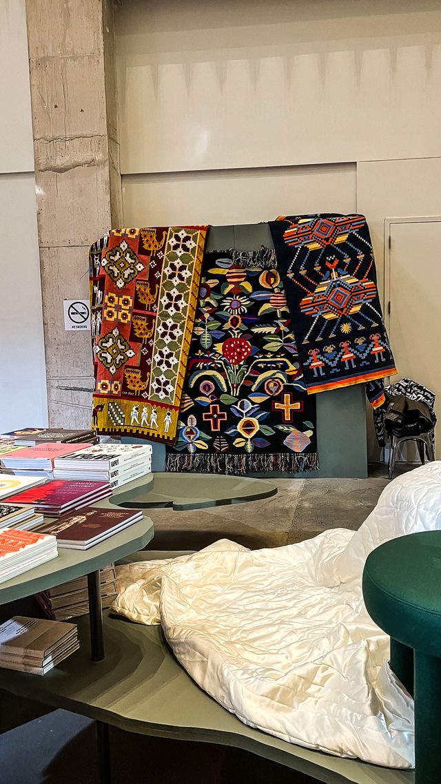woven tapestries above green book display table