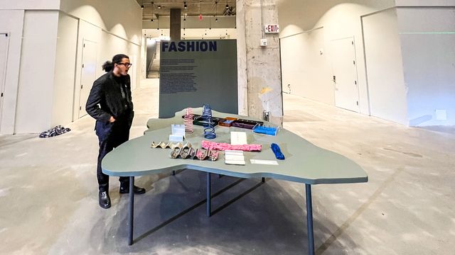 fashion exhibit table with colorful objects and text panel