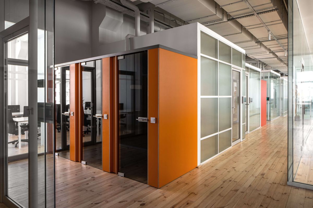 orange phone booths along glass-walled office hallway