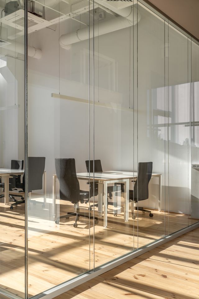 glass-partitioned meeting room with white desks