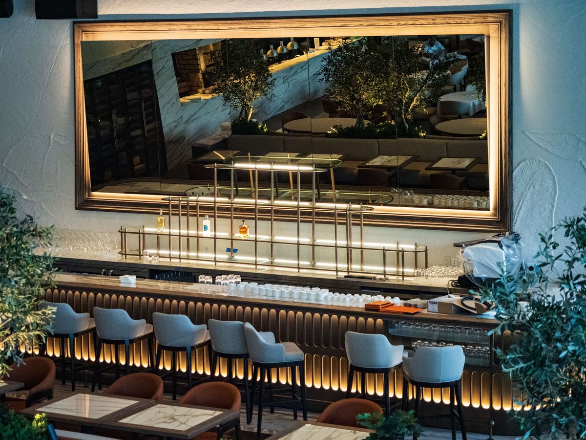 fluted wood bar with large framed mirror and stools