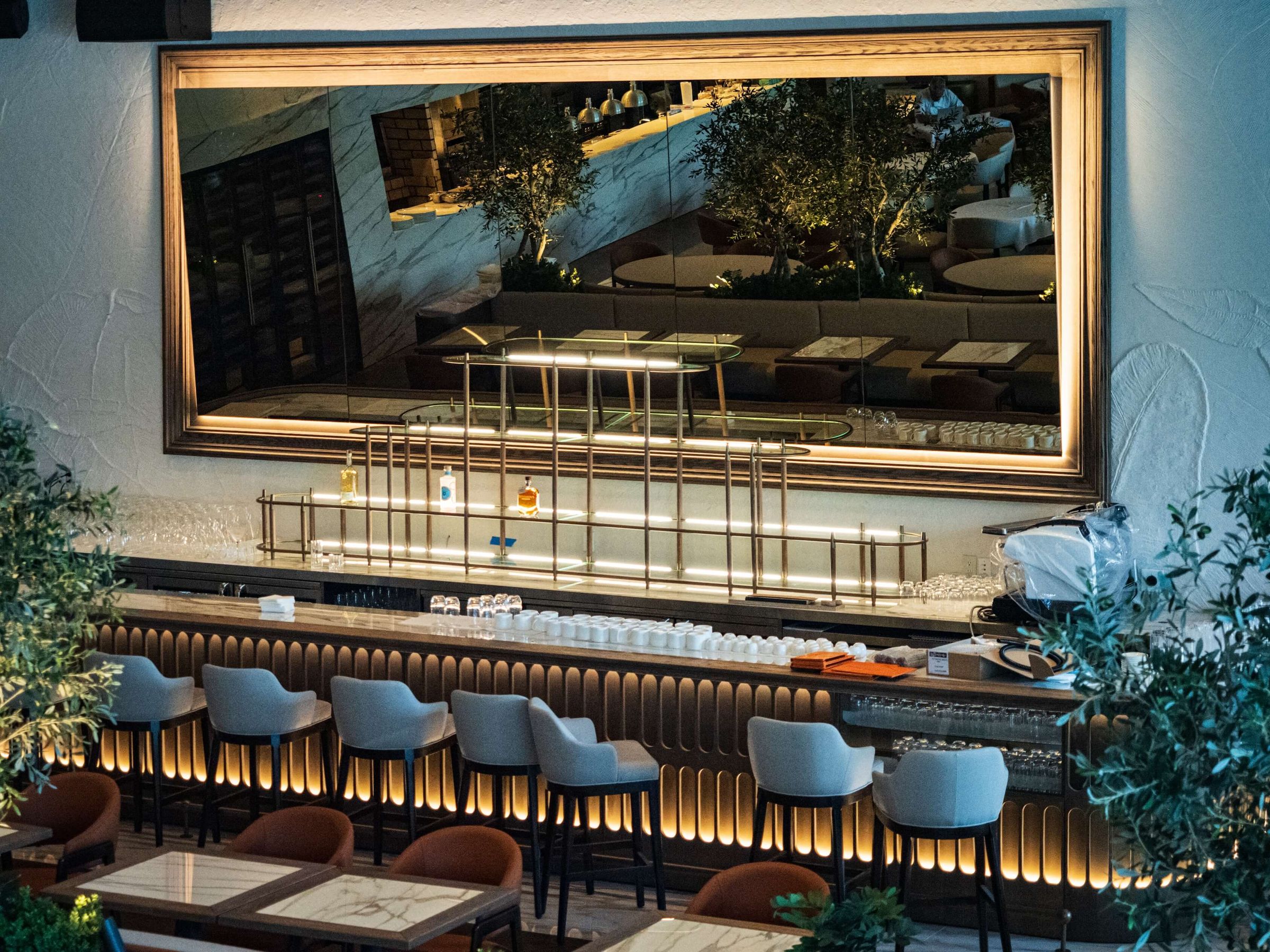 fluted wood bar with large framed mirror and stools