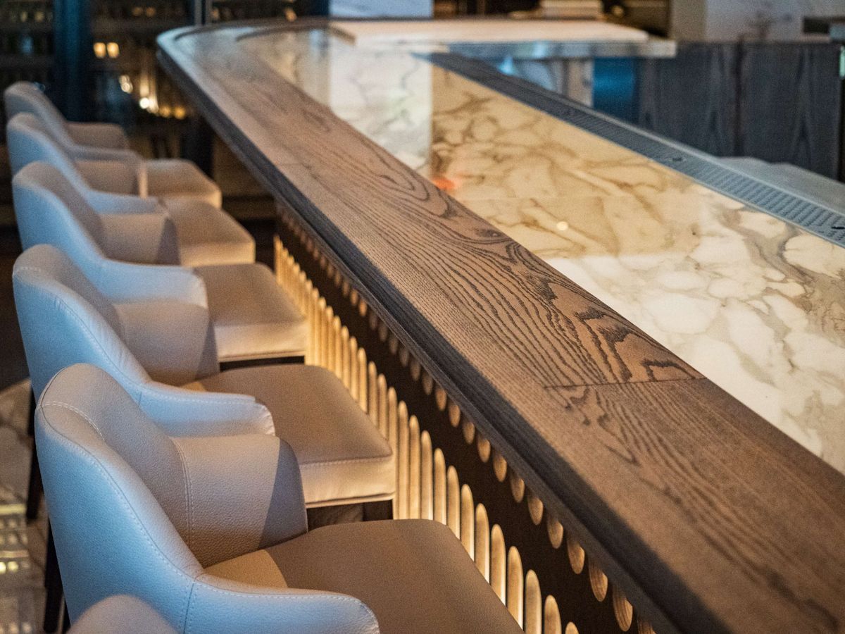 curved marble bar with slat base and grey stools