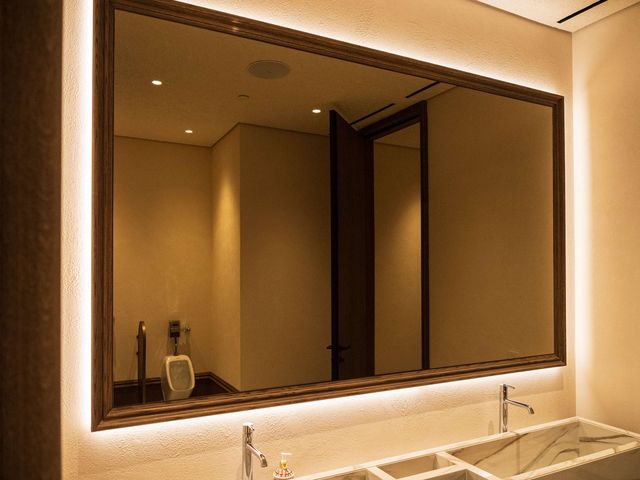 backlit mirror over marble trough restroom sinks