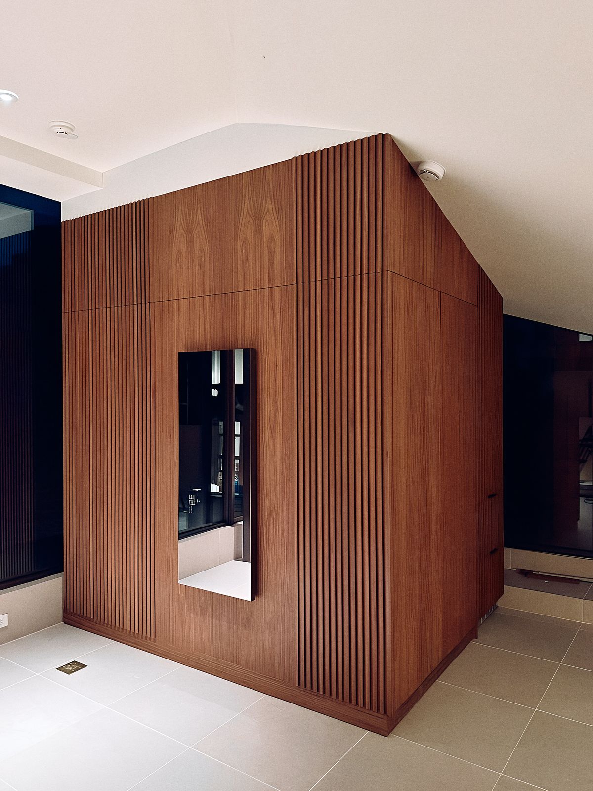 walnut slat wall wrapping a corner, with a training screen set flush in a plain panel