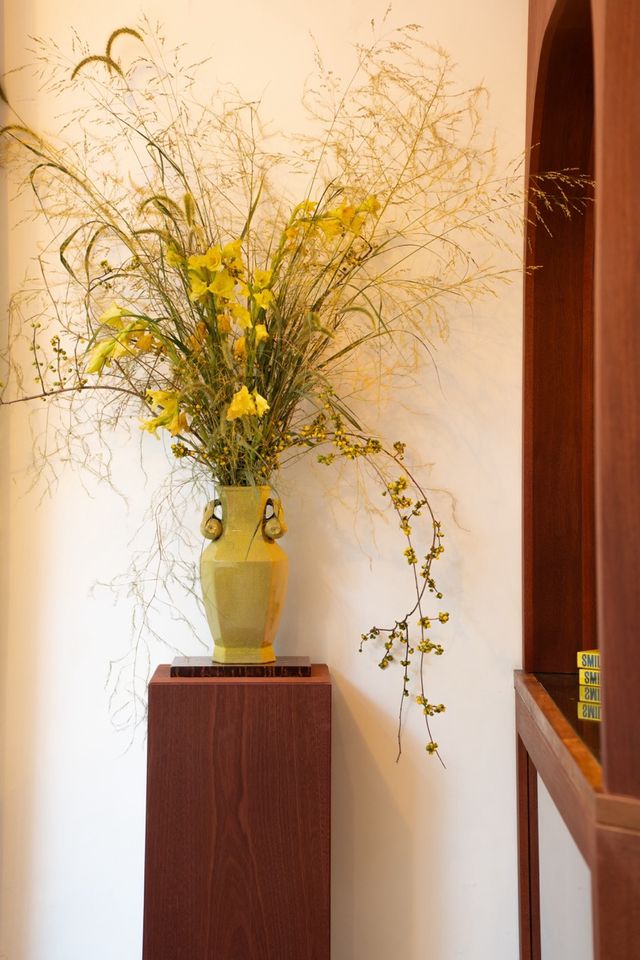 yellow vase floral arrangement on wood pedestal